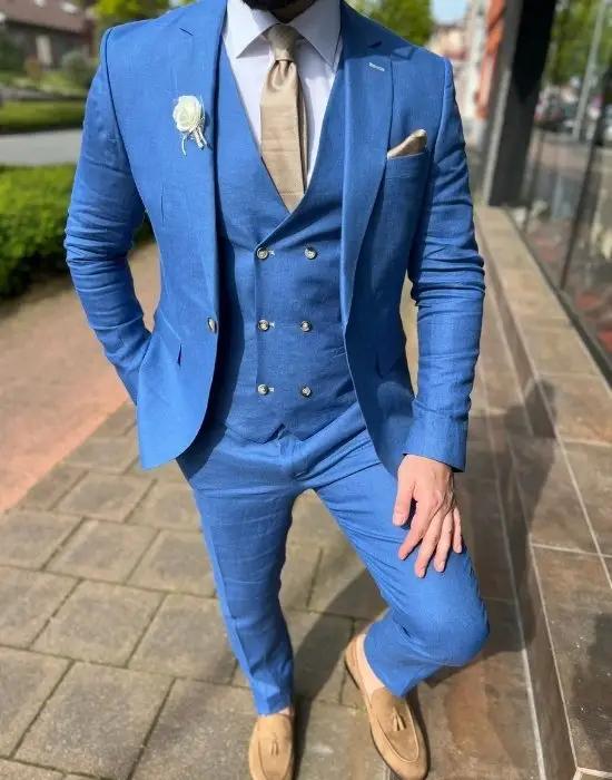 Costume bleu élégant avec cravate beige et mocassins.