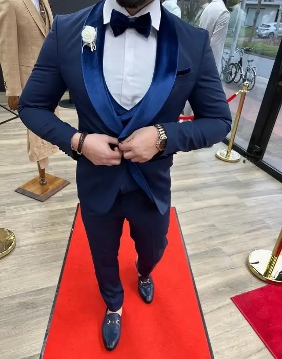 Homme en costume bleu avec noeud papillon sur tapis rouge