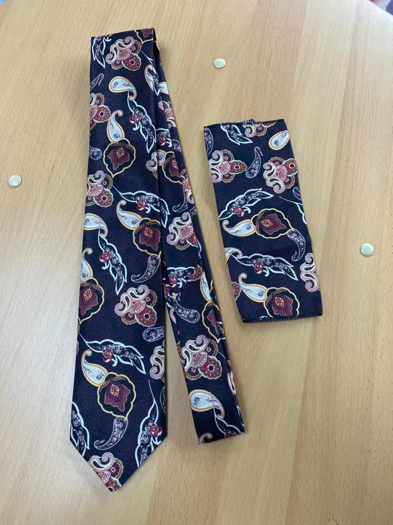 Cravate et pochette à motifs paisley sur table en bois