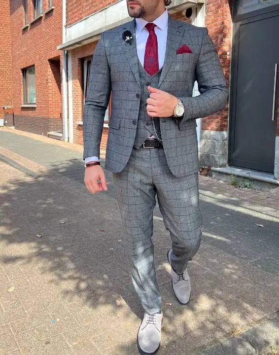 Homme en costume gris à carreaux avec cravate rouge