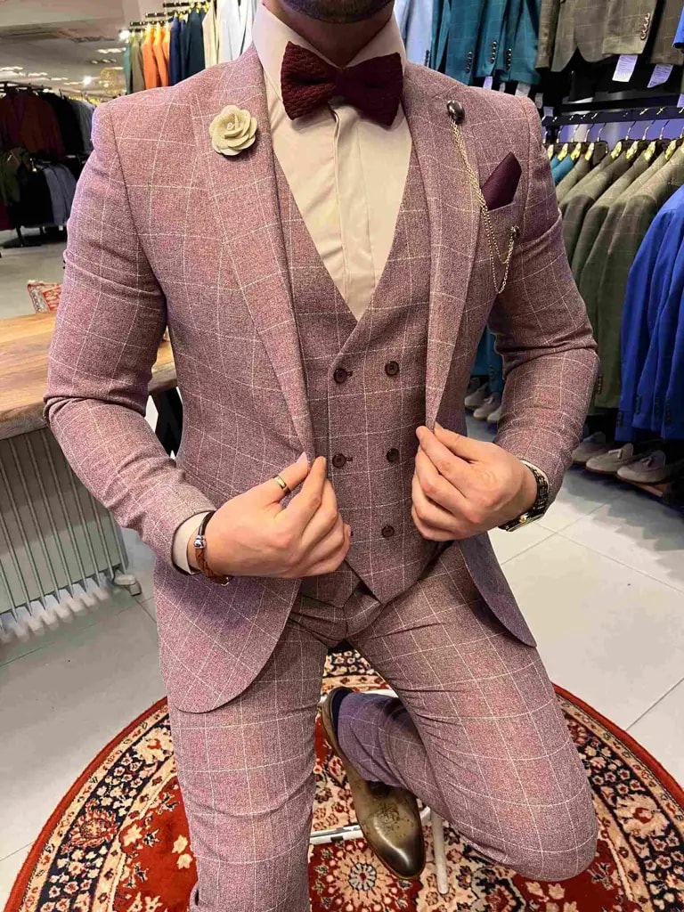 Homme portant un costume à carreaux rose avec nœud papillon