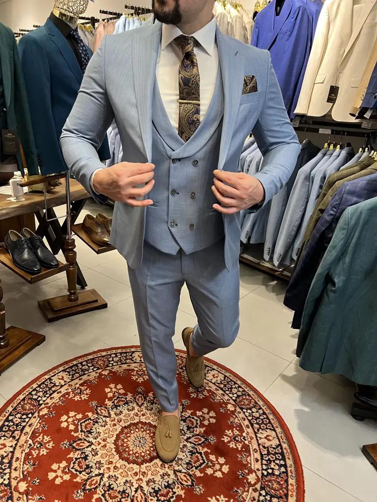 Homme portant un costume bleu clair avec gilet et cravate.