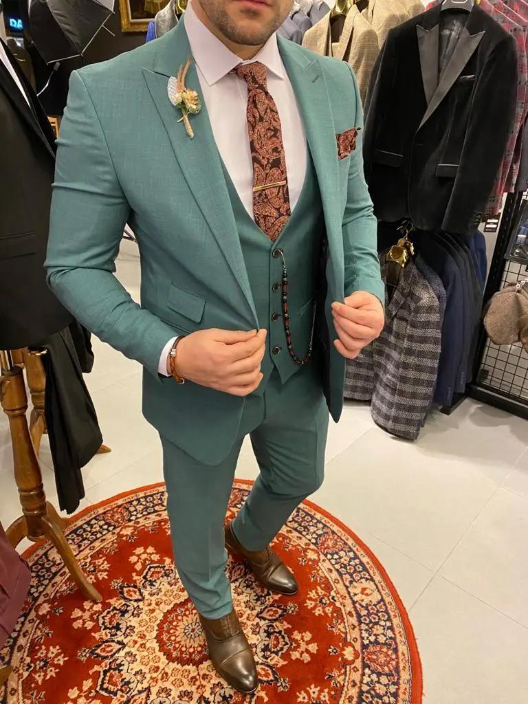 Homme en costume vert avec cravate brodée marron