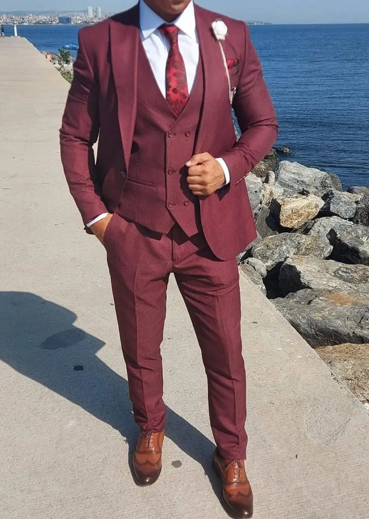 Homme en costume trois pièces bordeaux au bord de la mer