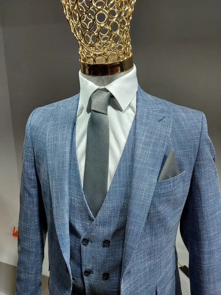 Costume trois pièces bleu avec chemise blanche et cravate grise