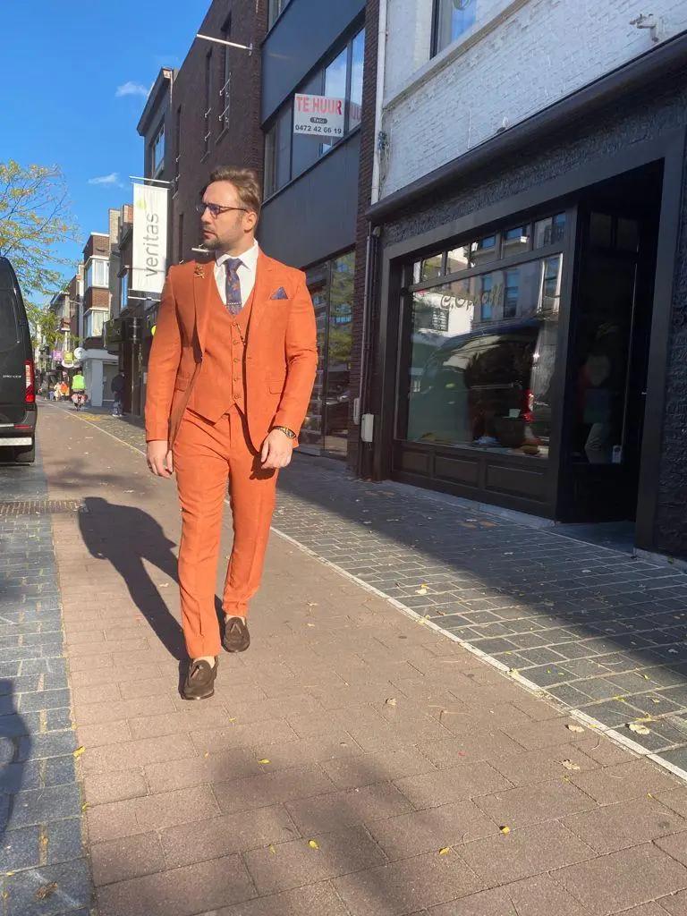 Homme en costume orange sur un trottoir ensoleillé