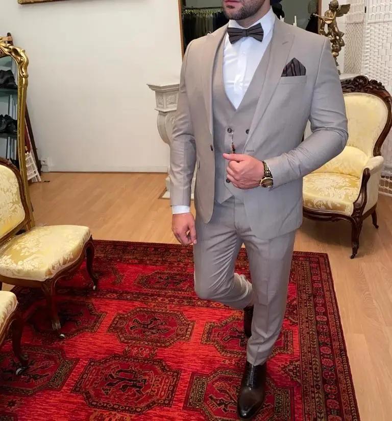 Homme en costume beige élégant avec nœud papillon.
