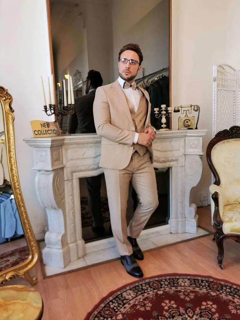Homme en costume beige élégant devant une cheminée